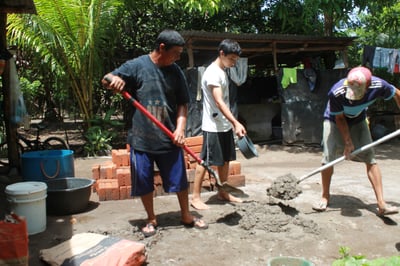 Three guys mixing dirt and water for building