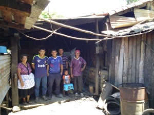 A smiling family stands under shelter